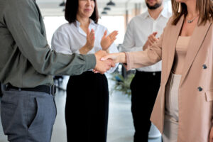 cropped two caucasian business people shaking hands modern office with colleagues man woman formal wear concept partnership communication copy space successful job coworking בוררות