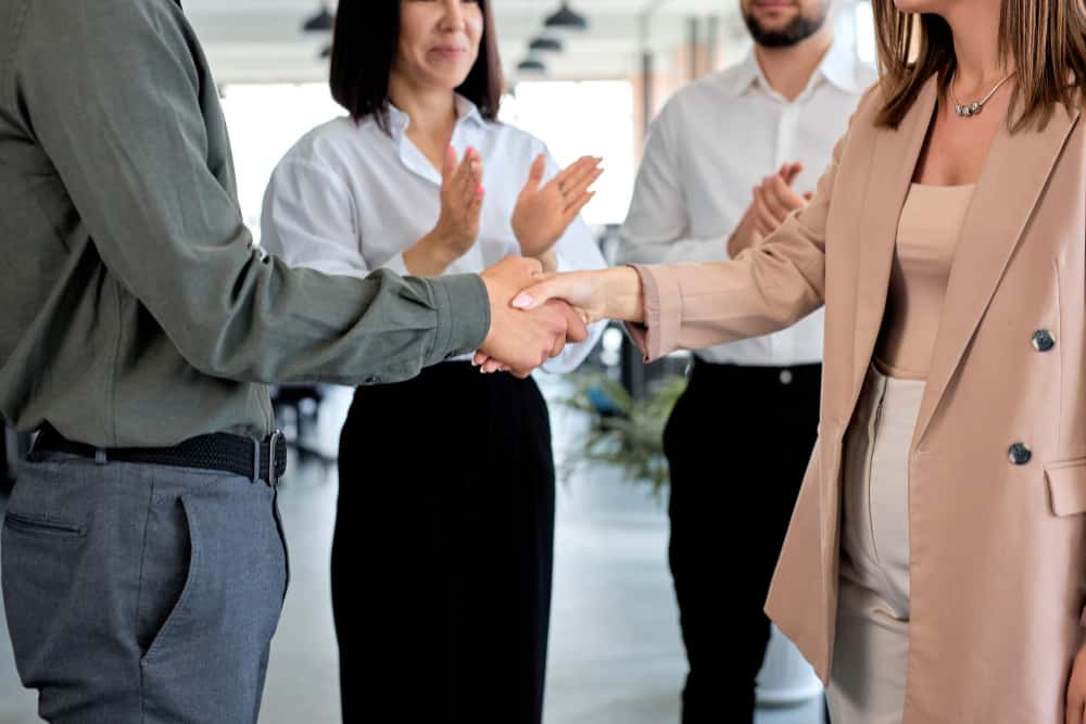 cropped two caucasian business people shaking hands modern office with colleagues man woman formal wear concept partnership communication copy space successful job coworking מונעים אי הבנות עם בוררות עסקית